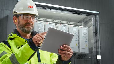 ABB Ability - Worker in a hardhat checks up electronics monitoring