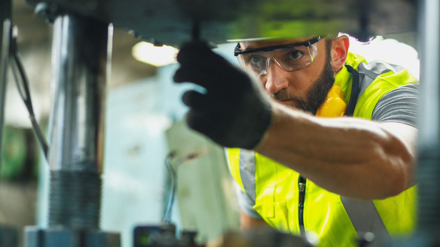 Close up hand industrial industrial plant with a tablet in hand, Engineer looking of working at industrial machinery setup in factory.